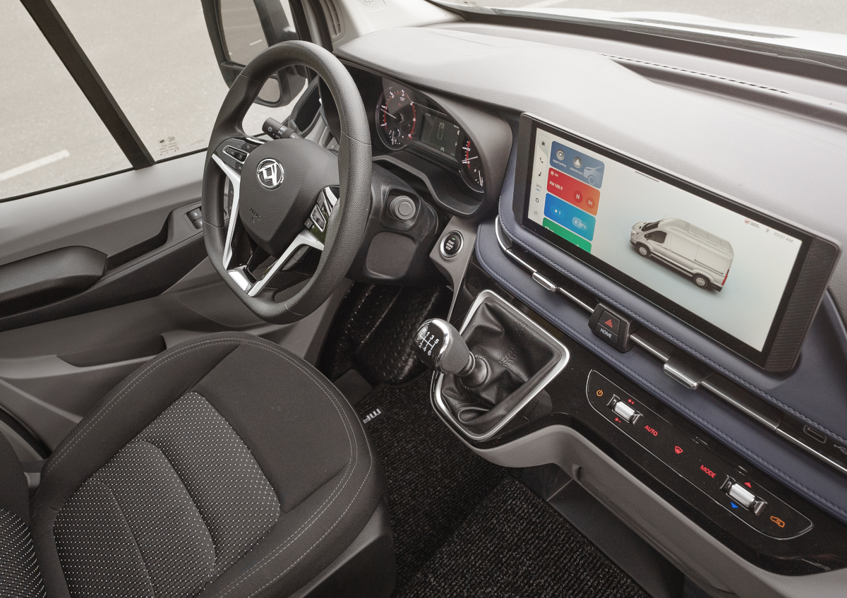 Innenansicht eines modernen Vans mit Lenkrad, Armaturenbrett und Touchscreen-Display.