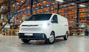 Ein weißer Transporter steht in einem Lager mit Regalen voller Waren im Hintergrund.