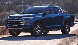 Maxus T90 EV Pickup auf einer Straße, umgeben von bewaldeter Landschaft, in blauem Farbton.