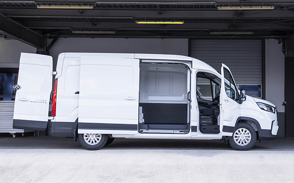 Weißer Transporter mit offenen Türen, sichtbar im Innenraum, vor einer Garagentür.